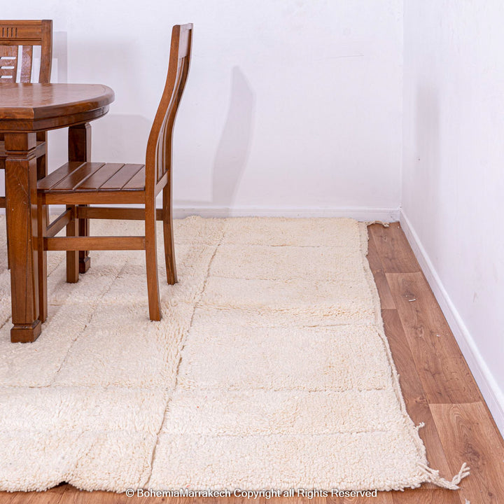 Minimalist Moroccan Berber rug in off-white wool under a wooden dining set, showcasing modern grid design and plush texture.