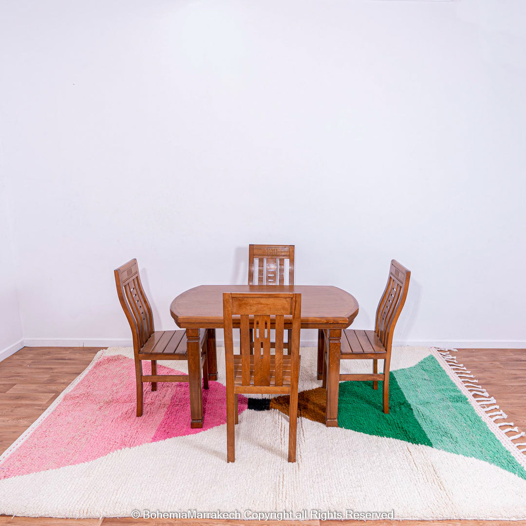 Dining area with wooden table set on a pink and green Moroccan Berber rug