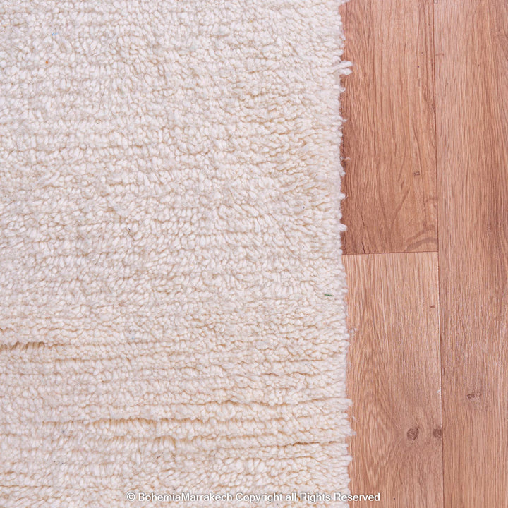 Close-up of natural wool Moroccan Berber rug on wooden floor, highlighting traditional craftsmanship and soft texture.