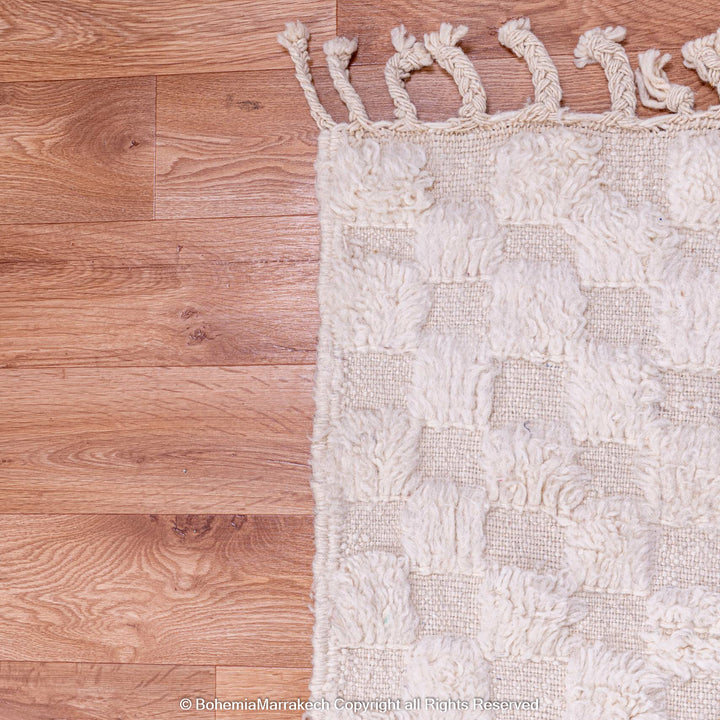 White Checkered Moroccan Rug on wooden floor, handmade from wool, showing textured Berber design. Perfect for Scandinavian interiors.