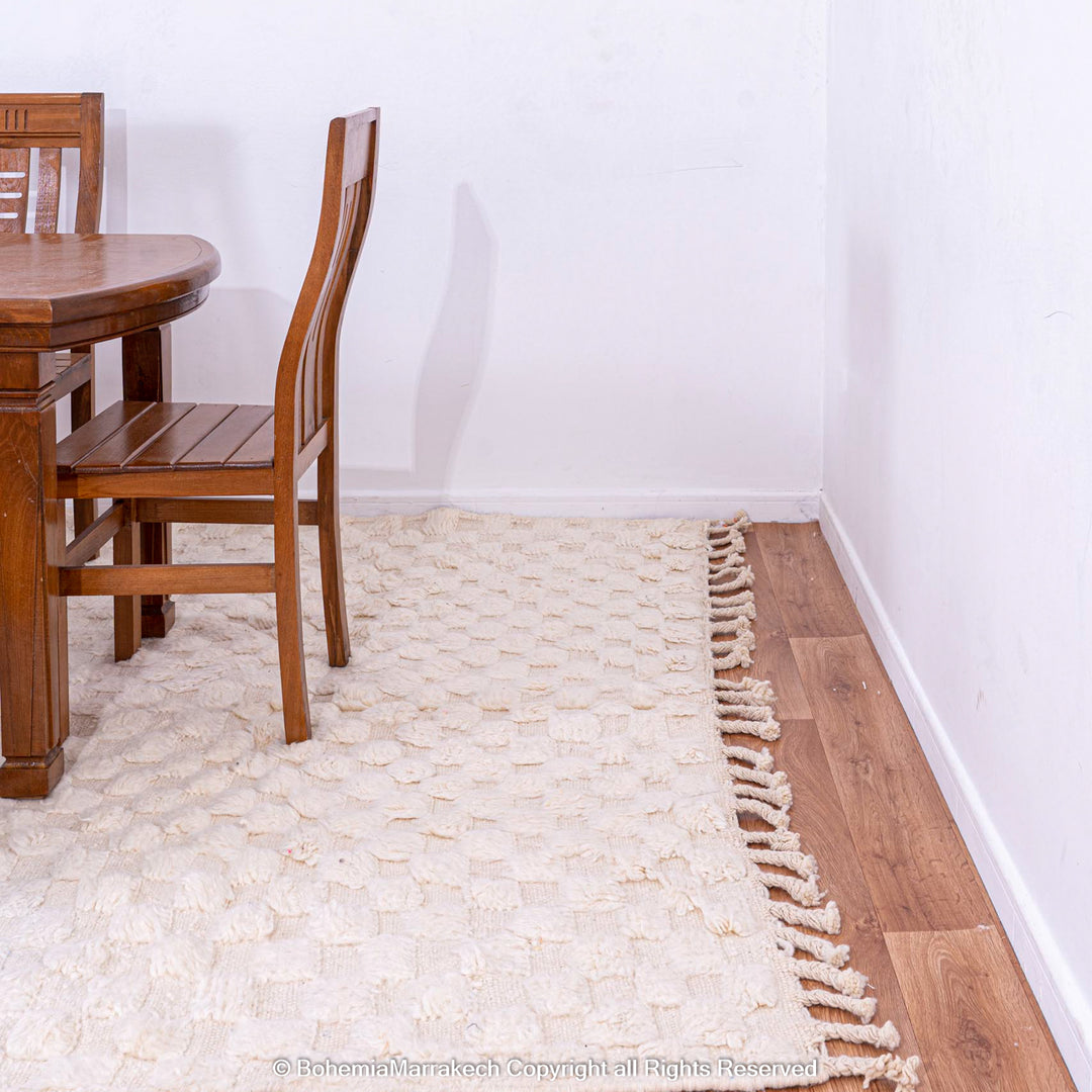 Cozy dining area with a white checkered Moroccan wool rug, adding warmth and texture, handwoven by Berber artisans in a minimal style.