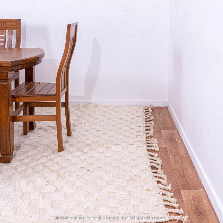 Cozy dining area with a white checkered Moroccan wool rug, adding warmth and texture, handwoven by Berber artisans in a minimal style.
