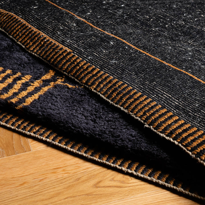 Dark Charcoal Moroccan Rug with Golden Pattern on a wooden floor, showcasing intricate Berber design and hand-detailed borders.