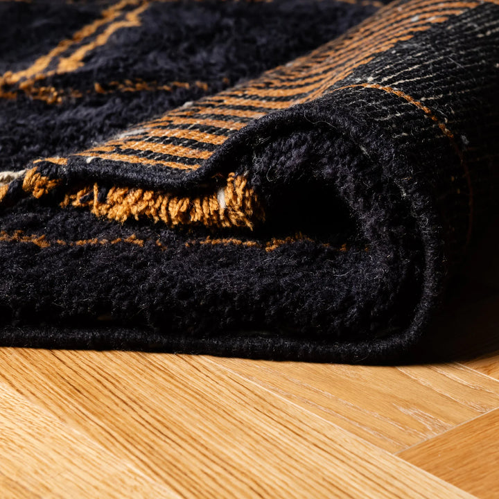 Close-up of a handmade dark charcoal Moroccan rug with golden pattern, featuring hand-detailed borders. Perfect as a Moroccan wool rug.