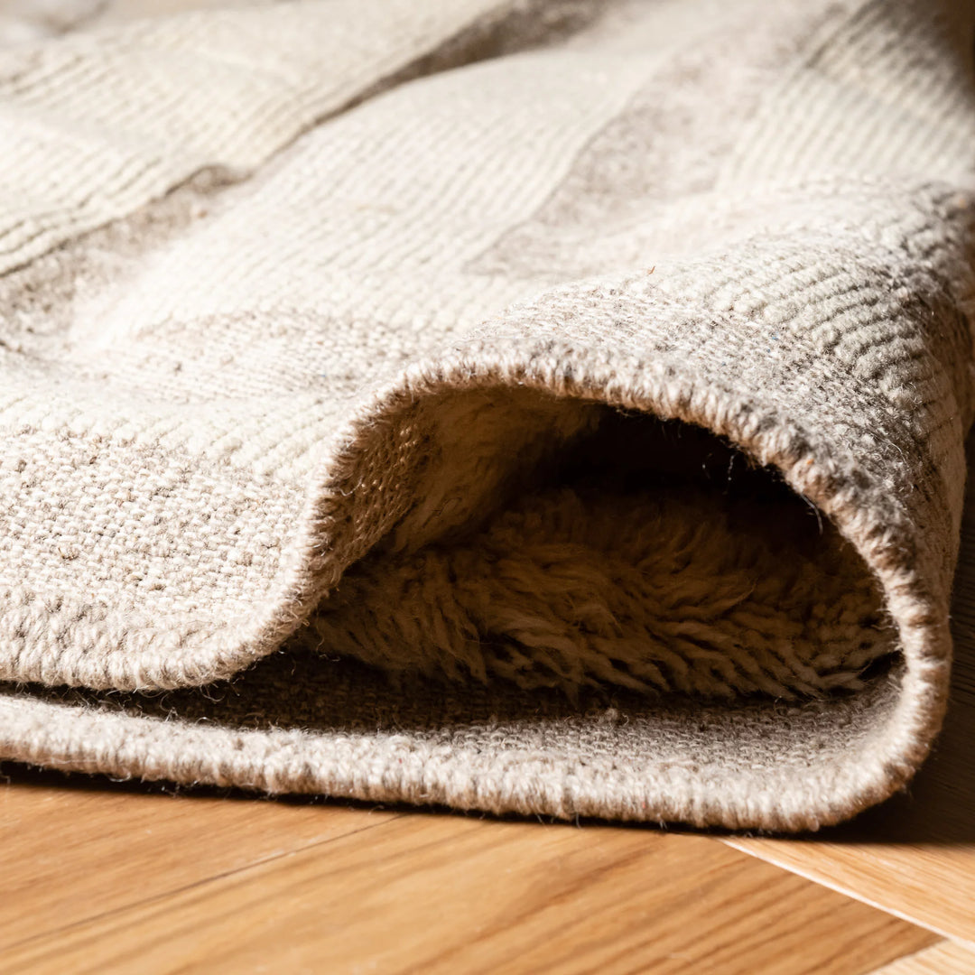 Close-up of a Geometric Beni Mrirt Moroccan wool rug with cream maze-like patterns on a wooden floor.