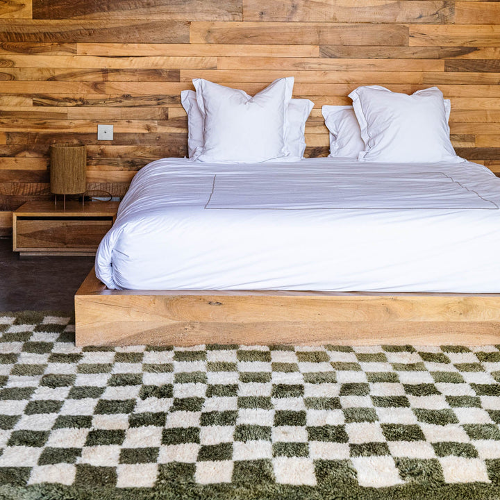 Green checkerboard Moroccan wool rug in cozy bedroom, handwoven by Berber artisans, perfect for modern interiors.