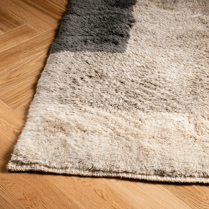 Handmade Moroccan wool rug with modern color blocks in neutral tones on wooden floor, perfect for minimalist or boho interiors.