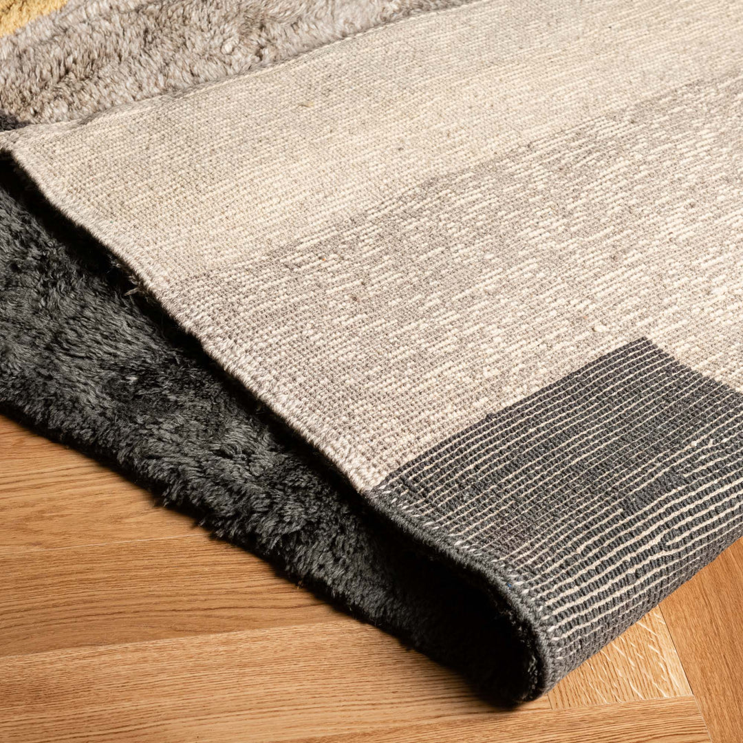 Handwoven Moroccan wool rug in neutral tones on wooden floor, showcasing texture and modern design. Perfect for minimalist decor.