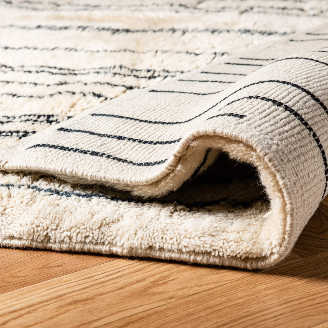 Close-up of handmade Moroccan wool rug with abstract linear design, showcasing its plush shag texture and intricate weaving.