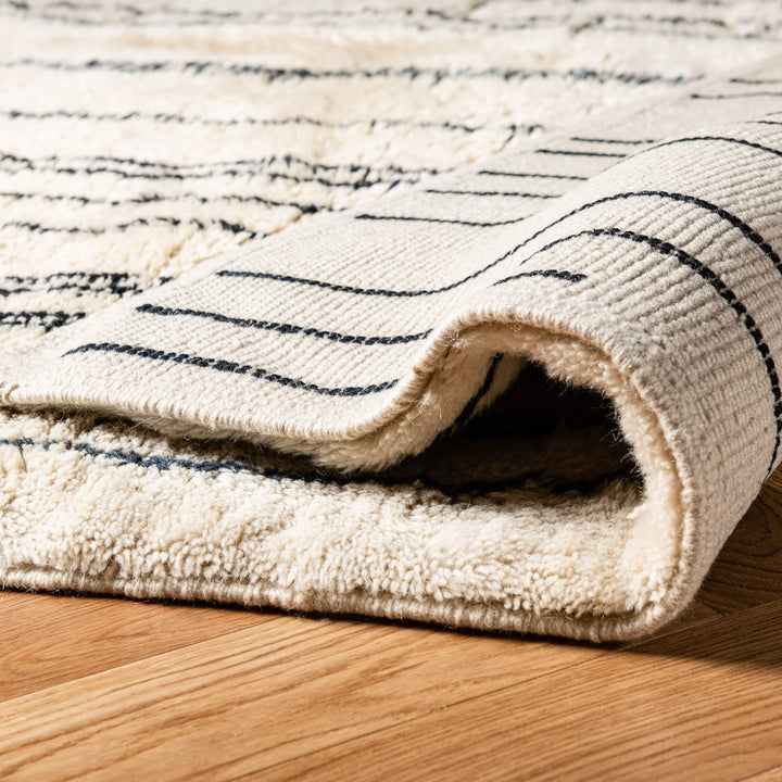 Close-up of handmade Moroccan wool rug with abstract linear design, showcasing its plush shag texture and intricate weaving.