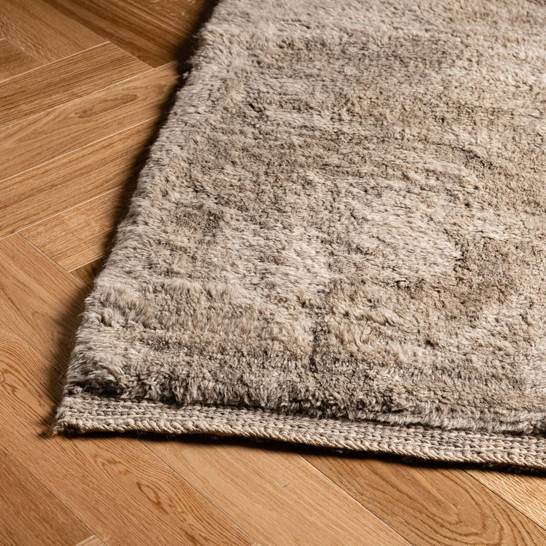 Handmade Moroccan wool rug with geometric line pattern on wooden floor, ideal as a Moroccan Berber carpet. Rugs from Morocco for sale.