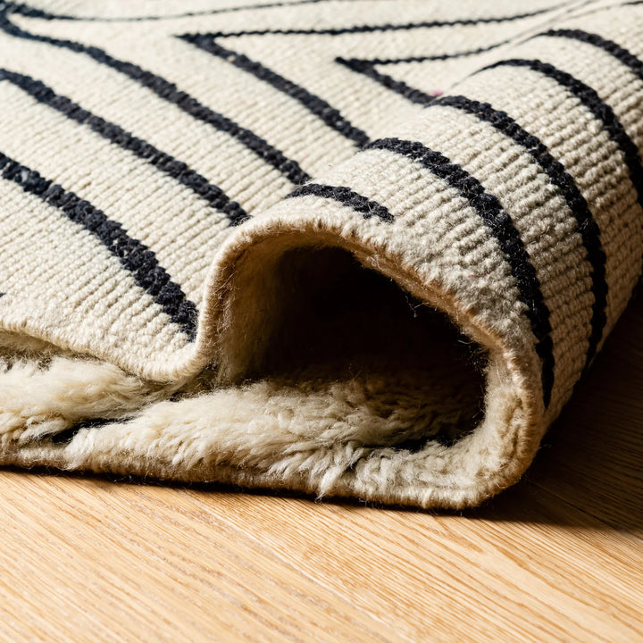 Close-up of a handwoven black and white Moroccan Berber runner rug, showcasing detailed natural wool texture and traditional patterns.