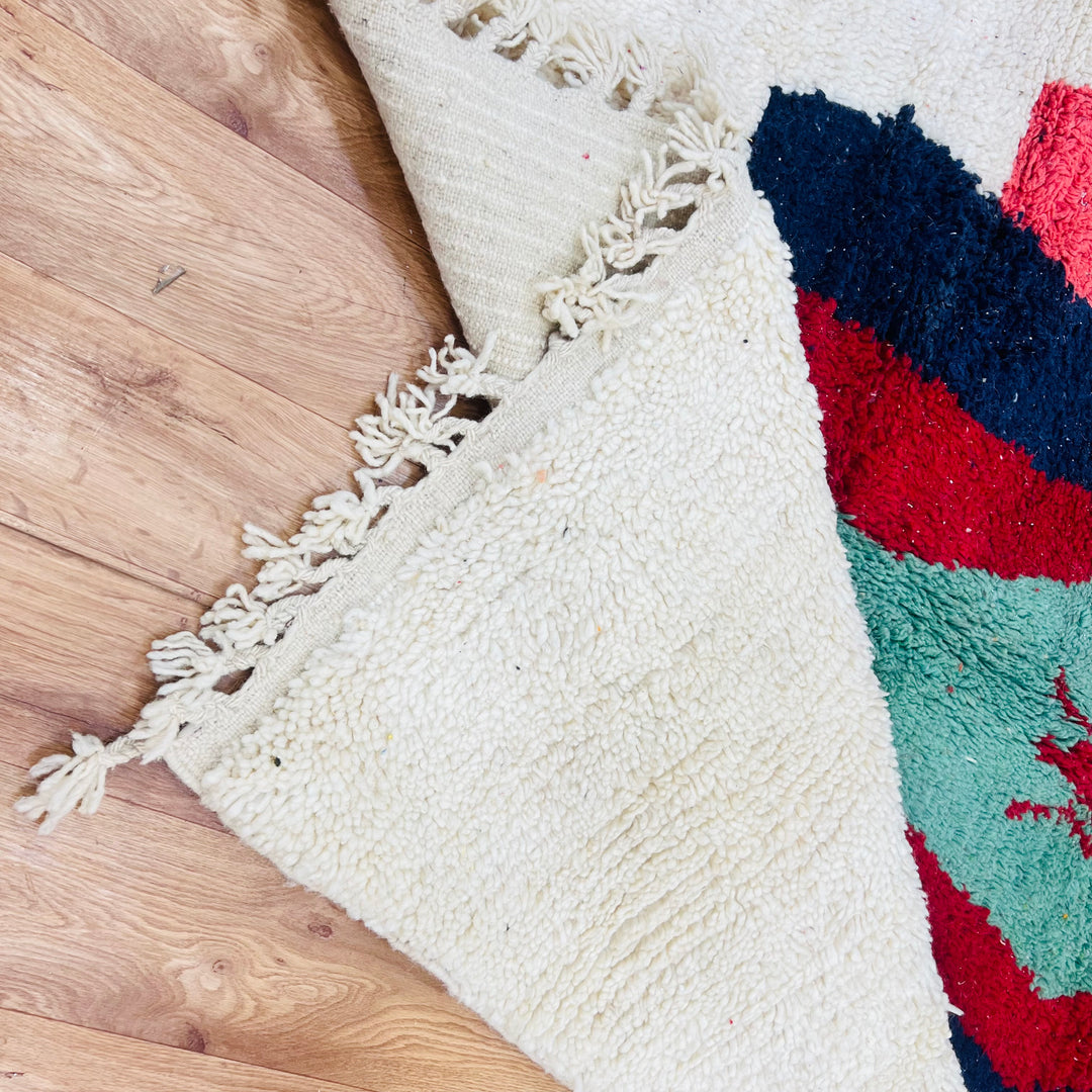 Vintage Moroccan Berber rug with green lozenge motif and colorful wool design on hardwood floor.
