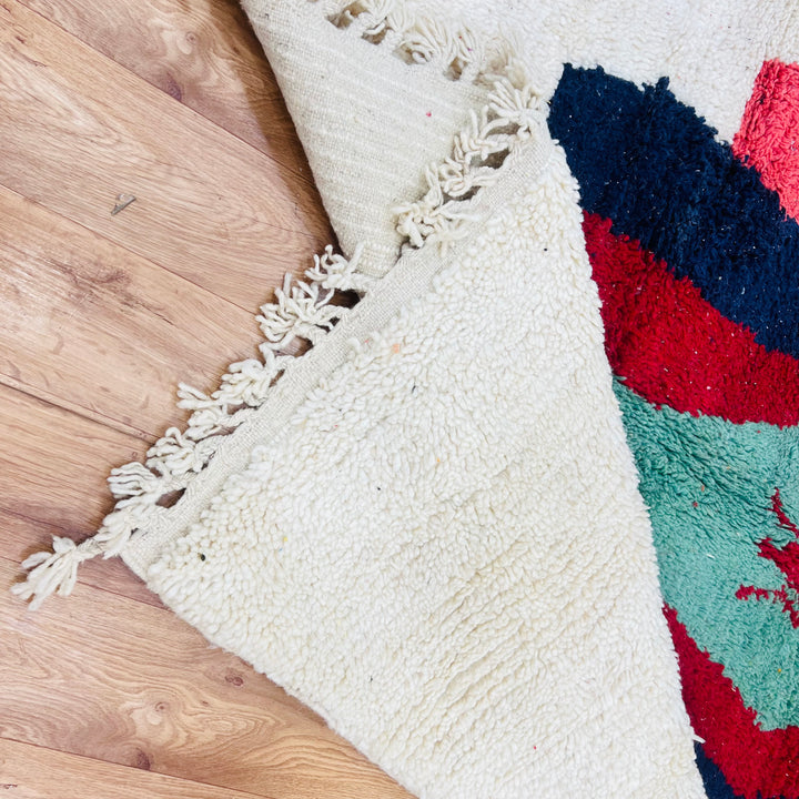 Vintage Moroccan Berber rug with green lozenge motif and colorful wool design on hardwood floor.