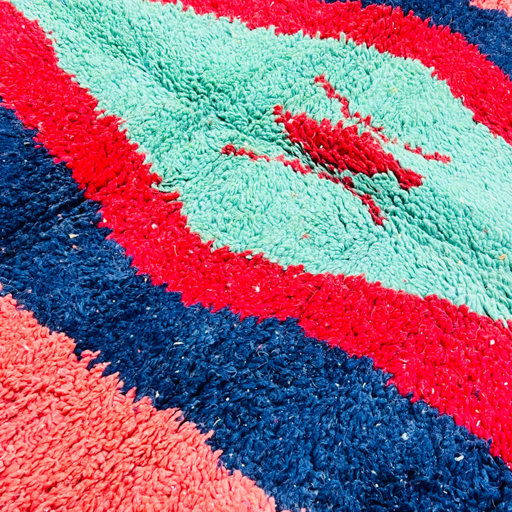 Vintage Moroccan Berber rug with green lozenge motif, red and navy borders, handwoven wool carpet, vibrant colors, traditional design.