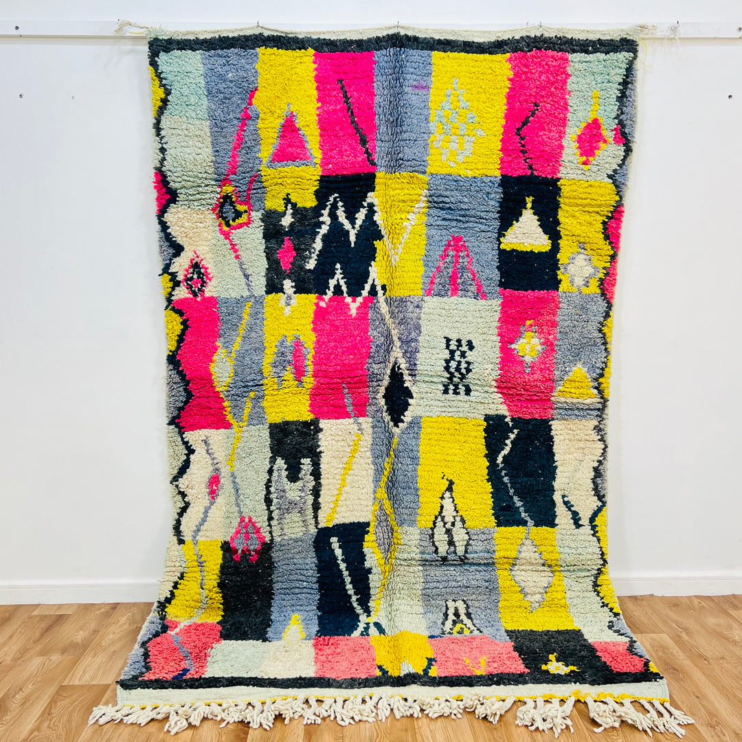 Vintage Moroccan wool rug 8x5 ft with bold tribal colors, handwoven Berber area rug featuring pink, yellow, black, and blue patterns.