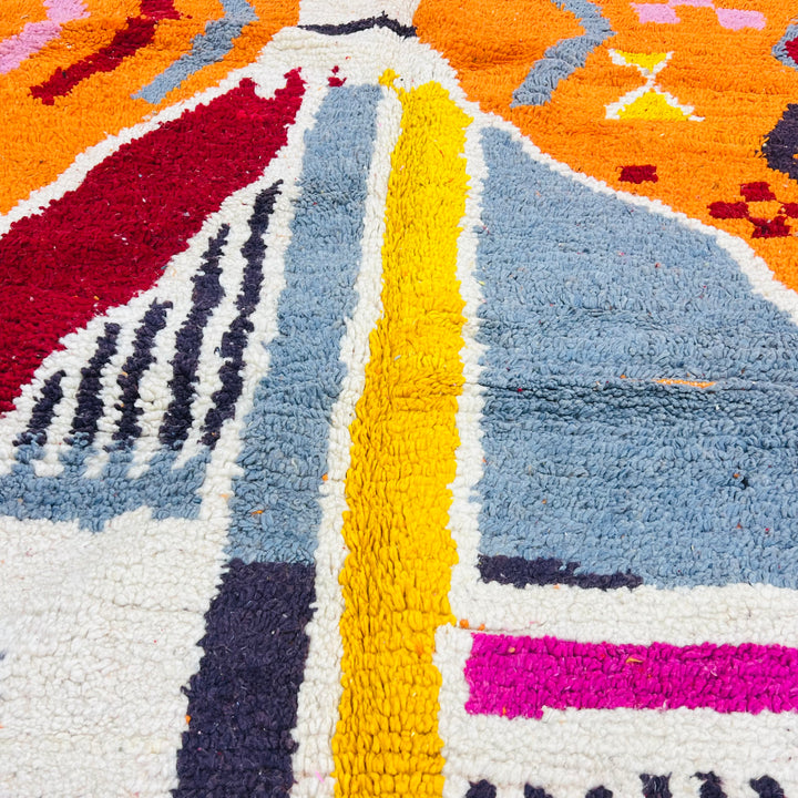 Close-up of a vintage Moroccan rug with abstract design in orange, blue, red, and pink tones. Handcrafted Berber wool rug from Morocco.