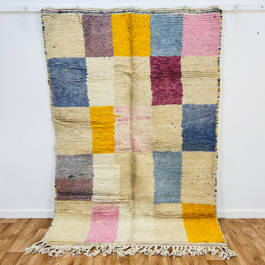 Colorful vintage Moroccan rug with geometric patterns in pink, yellow, blue, and brown, handmade by Berber artisans.