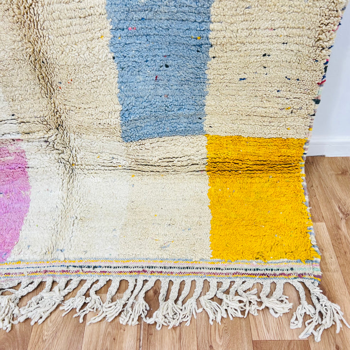 Colorful vintage Moroccan Berber rug with geometric patterns in pink, blue, and yellow, ideal for boho and eclectic interiors.