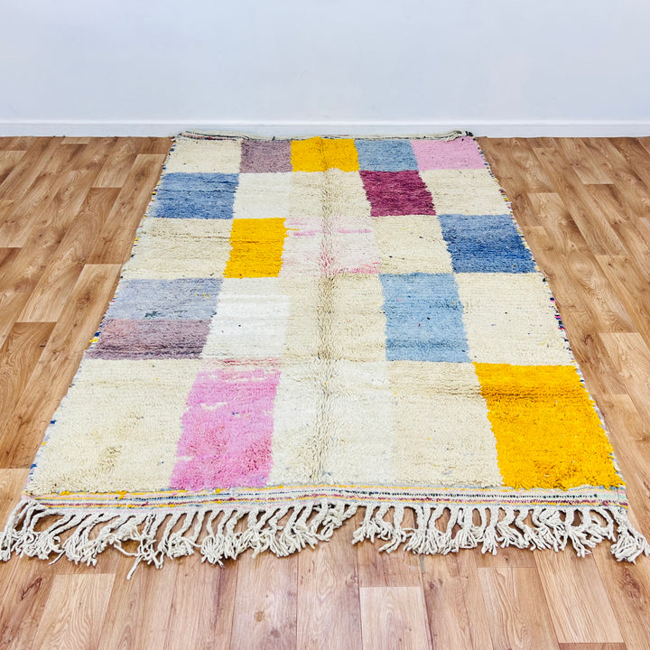 Colorful vintage Moroccan Berber rug with geometric patterns in pink, yellow, and blue. Handmade traditional Moroccan carpet.