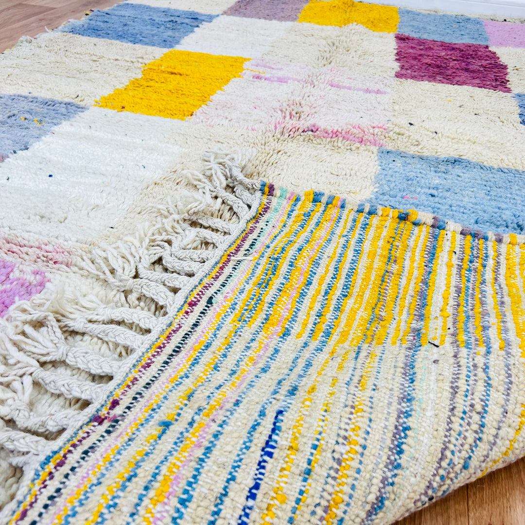 Colorful vintage Moroccan rug with geometric patterns in pink, yellow, blue; handmade by Berber artisans. Perfect for eclectic decor.