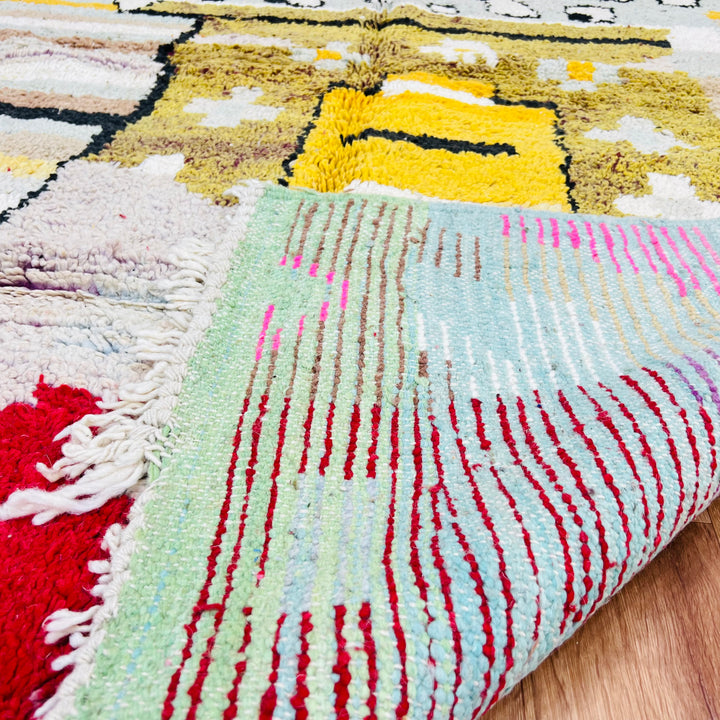 Vintage Moroccan rug with abstract tribal motifs in mustard, red, pink, and blue. Traditional Moroccan Berber rug in vibrant colors.