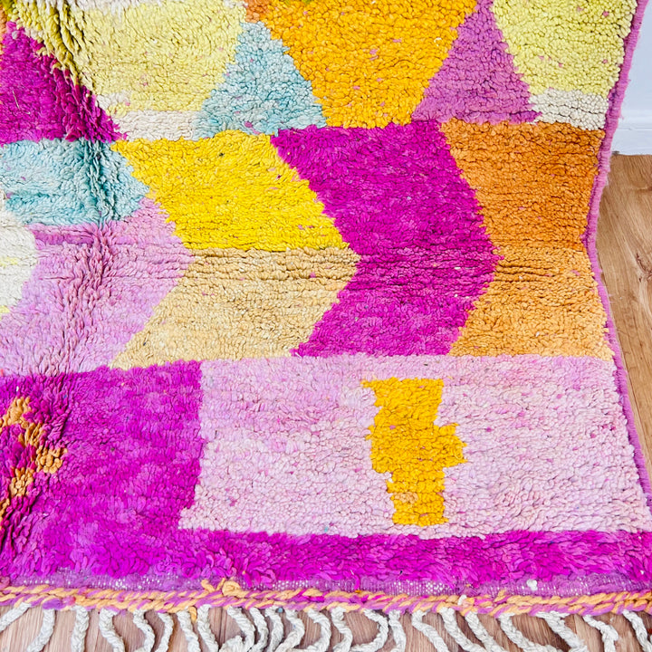 Vibrant geometric Moroccan wool rug with diamonds in ochre, olive, terracotta, pink, and yellow hues, handwoven by Berber artisans.