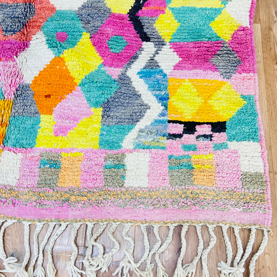 Colorful Moroccan Berber rug with pink, yellow, and teal diamond patterns, handwoven wool, showcasing traditional tribal symbols.