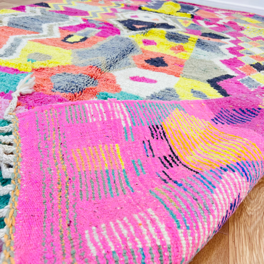 Colorful Moroccan Berber Rug with tribal patterns, pink, coral, teal, and yellow tones, handwoven wool, traditional Moroccan decor.