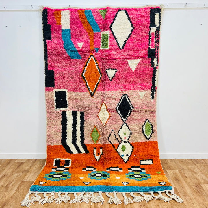 Colorful Moroccan wool rug 254x150 cm with vibrant pink, orange, blue tones and Berber diamond motifs, handmade by artisans.