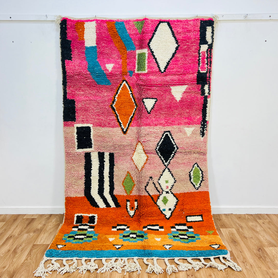 Colorful Moroccan wool rug with pink, orange, blue, and ivory tones, featuring Berber diamond motifs and tribal lines, 254 x 150 cm.