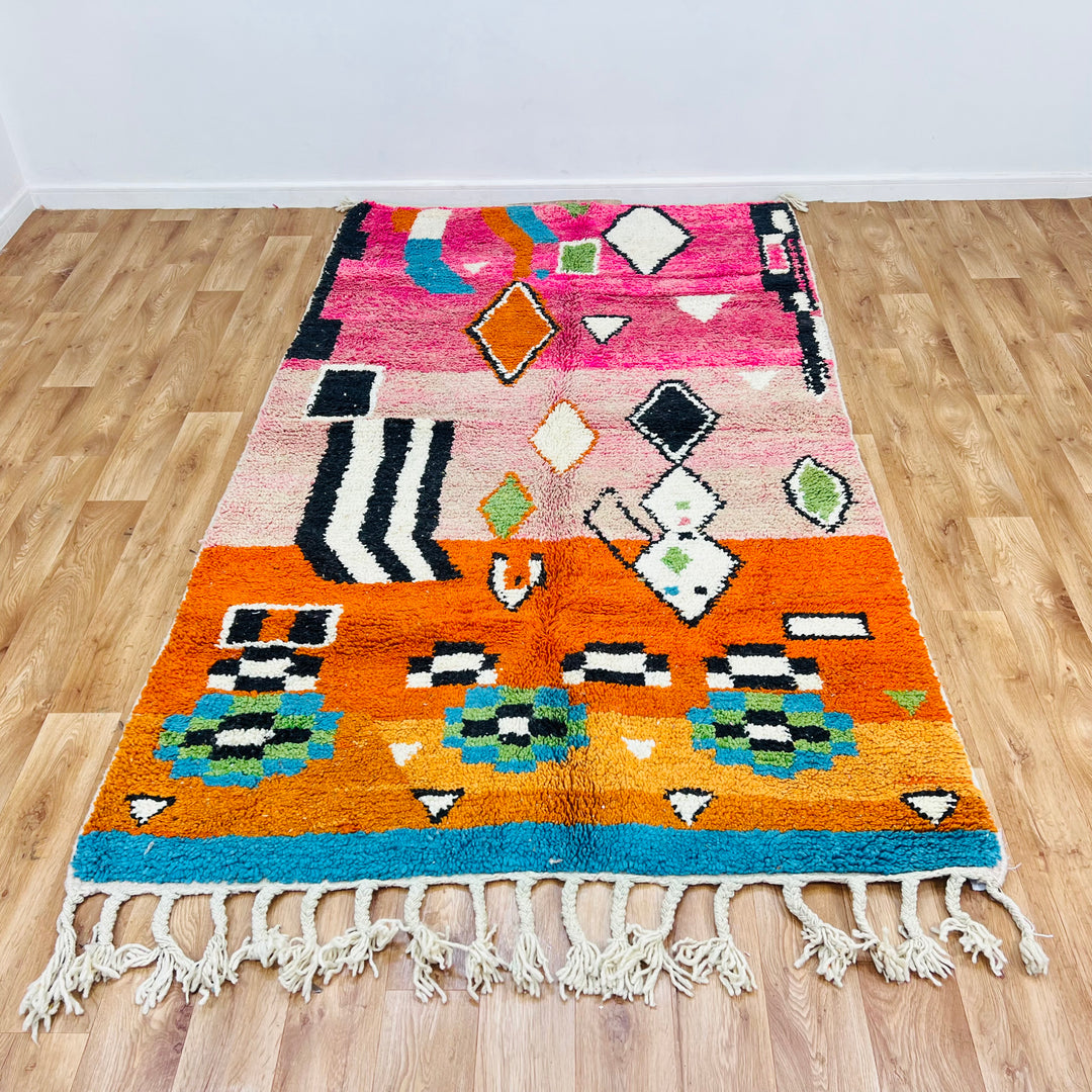 Colorful Moroccan wool rug with Berber motifs in pink, orange, blue, and ivory, 254 x 150 cm.