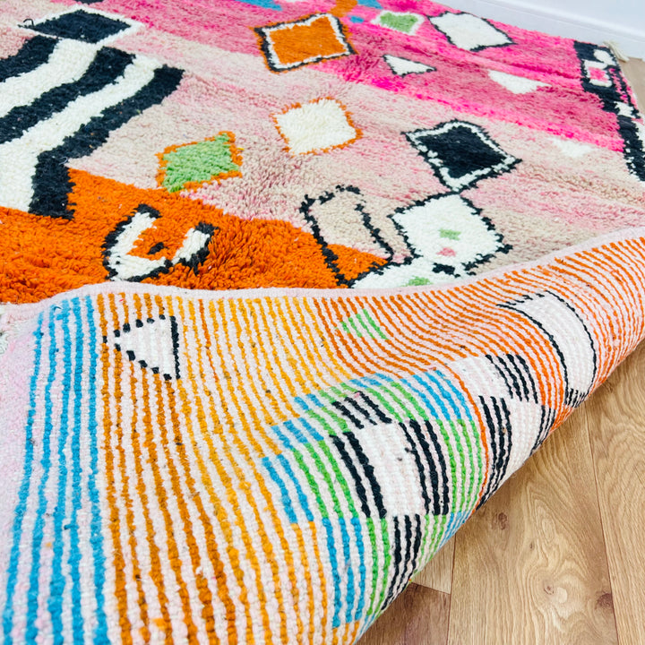 Colorful Moroccan wool rug with pink, orange, and blue tones, featuring diamond motifs and tribal designs, 254 x 150 cm.