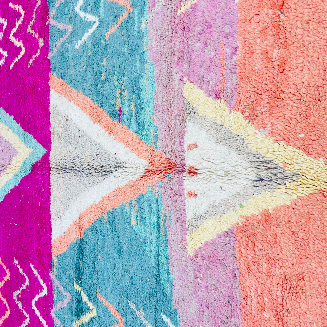 Colorful vintage Moroccan wool rug with V-shaped tribal motifs and zigzag patterns in magenta, turquoise, orange, and pink.