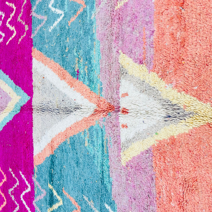 Colorful vintage Moroccan wool rug with V-shaped tribal motifs and zigzag patterns in magenta, turquoise, orange, and pink.