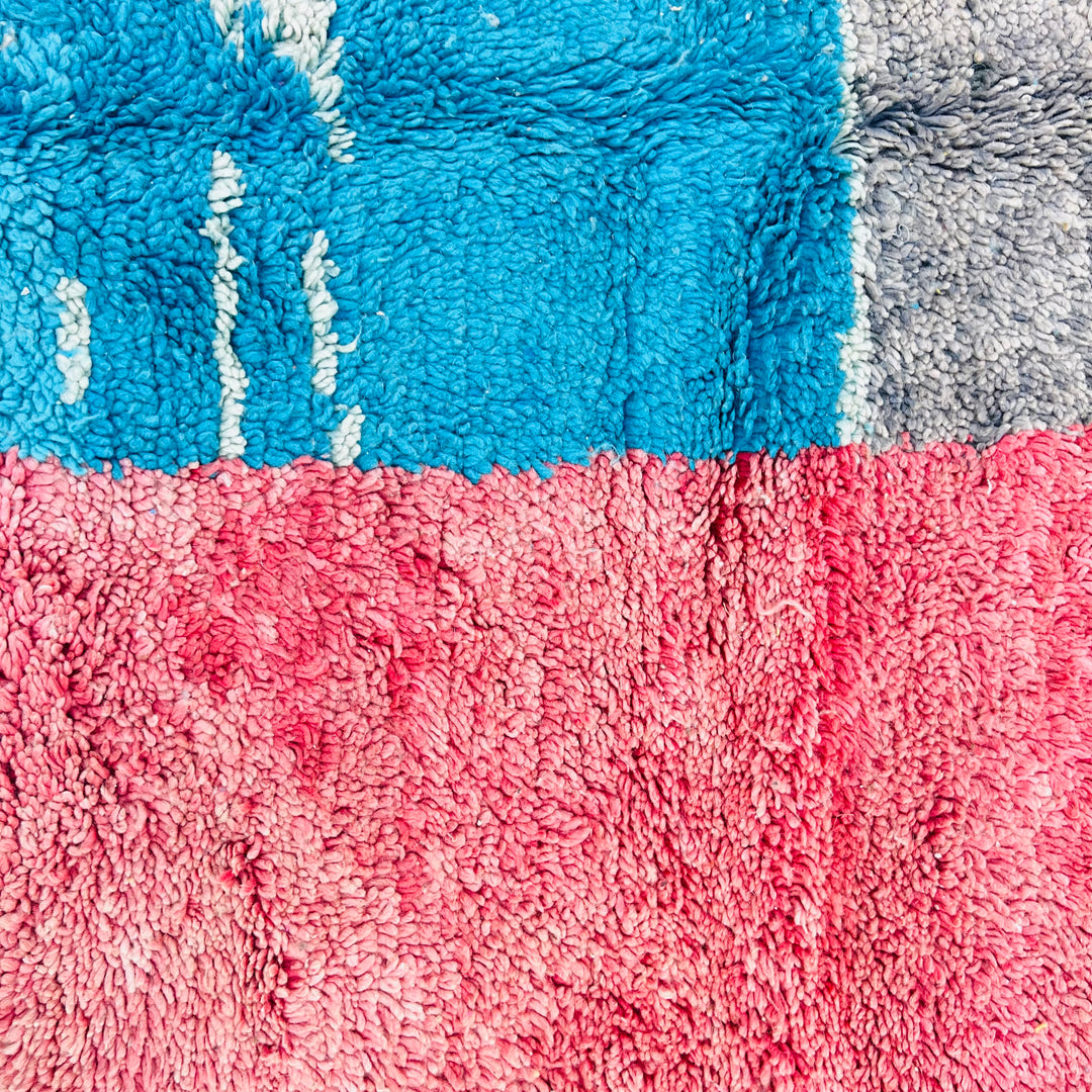 Close-up of a vintage Moroccan rug with blue, pink, and gray color blocks, woven with thick wool. Ideal for modern or traditional décor.