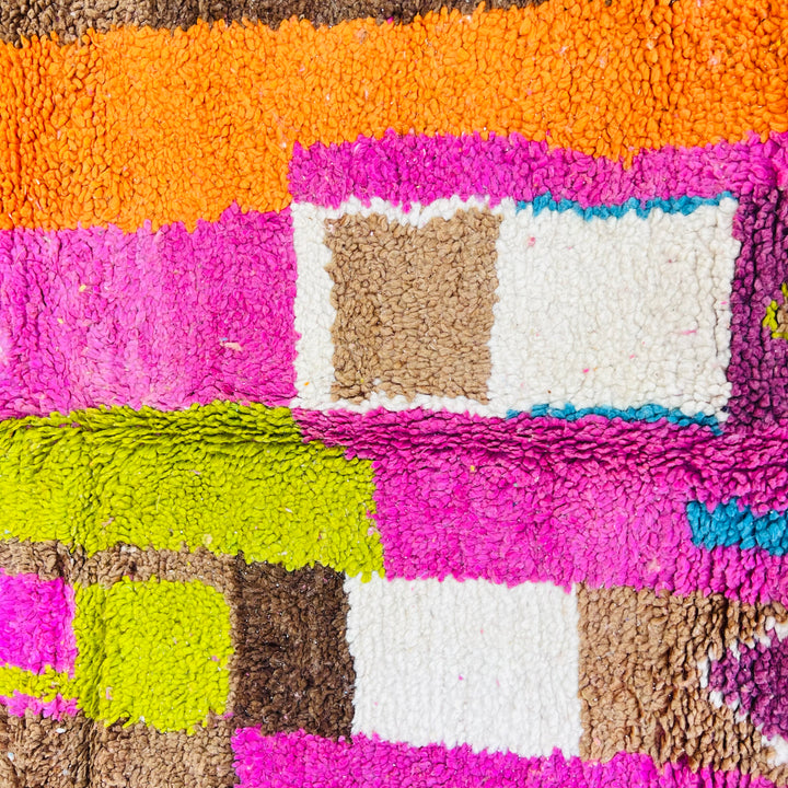 Vintage Moroccan Berber rug with vibrant pink, orange, teal, and lime geometric patterns, showcasing traditional artistry.