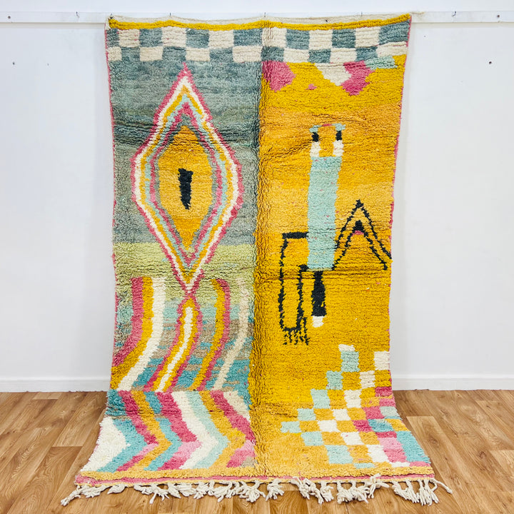 Vintage Moroccan rug with yellow field, abstract Berber symbols, geometric diamond medallion, and rainbow zigzags.