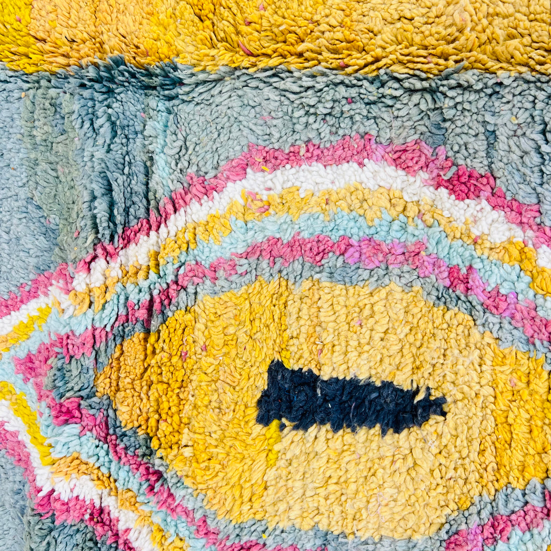 Close-up of a vintage Moroccan wool rug featuring bold abstract patterns in yellow, pink, and blue hues. Handwoven Berber design.