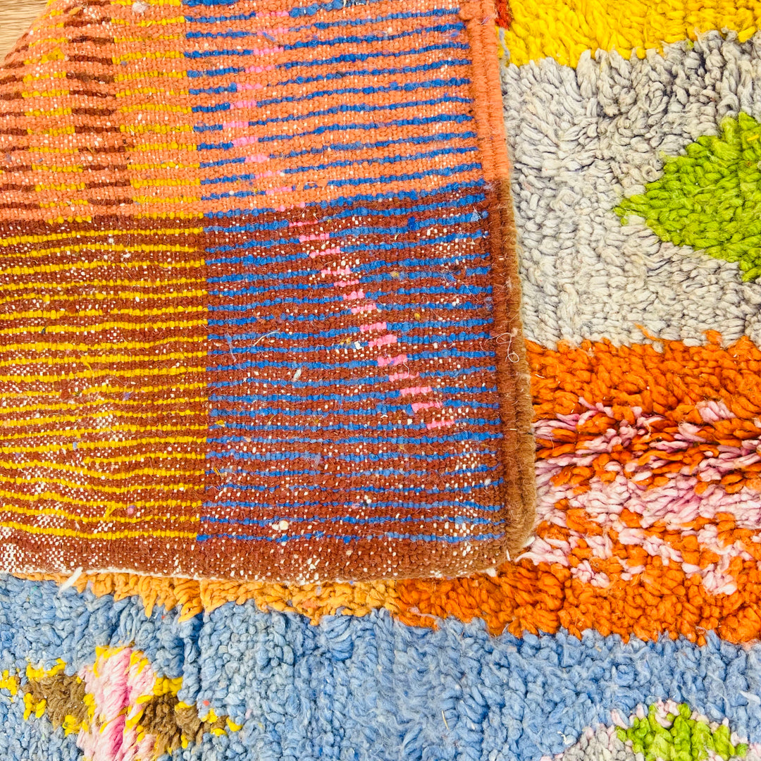 Handwoven vintage Moroccan rug with colorful Berber patterns in brown, red, yellow, blue, and orange, showcasing cultural heritage.