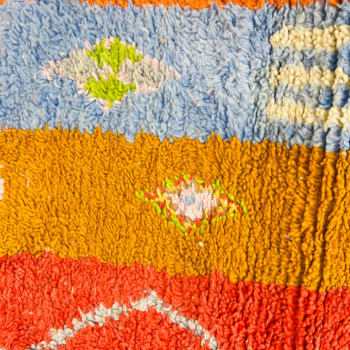 Colorful Moroccan rug with Berber symbols, featuring red, blue, orange, and green motifs. Handmade vintage Moroccan rug.