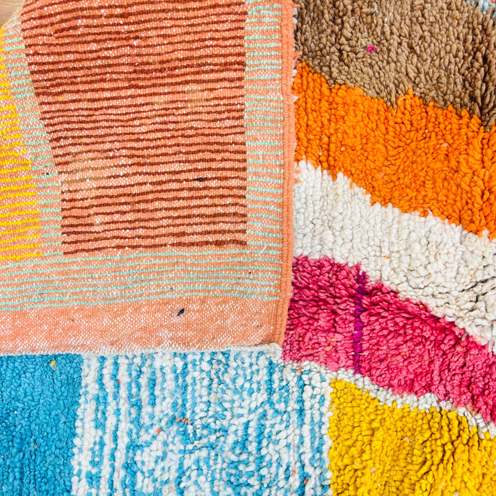 Colorful abstract Moroccan wool rug with vibrant geometric blocks in magenta, turquoise, yellow, orange, brown, and cream.