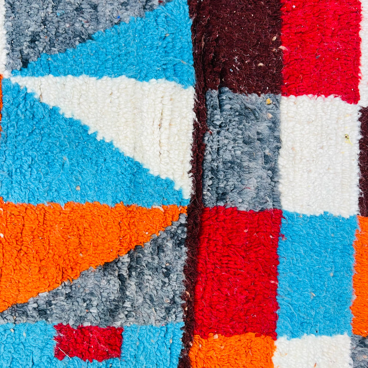 Bold geometric design on vintage Moroccan rug with burnt orange, sky blue, burgundy, and cream colors. Traditional Berber wool rug.