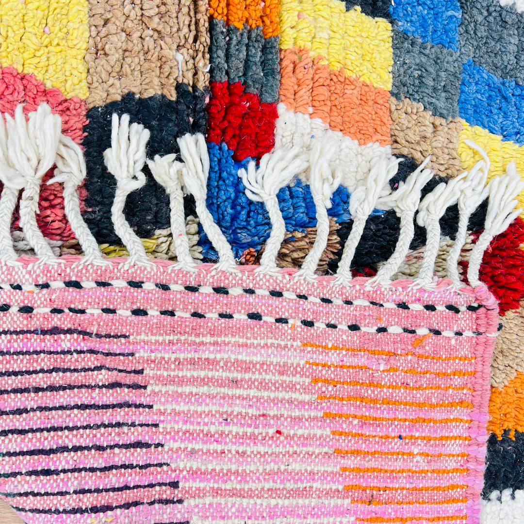 Bold geometric vintage Moroccan rug with vibrant colors, handwoven texture, and fringe detailing, ideal for living rooms or creative spaces.