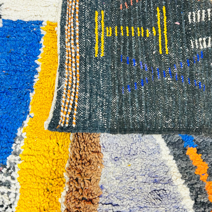 Colorful abstract vintage Moroccan wool rug with geometric designs in yellow, orange, blue, and charcoal tones.