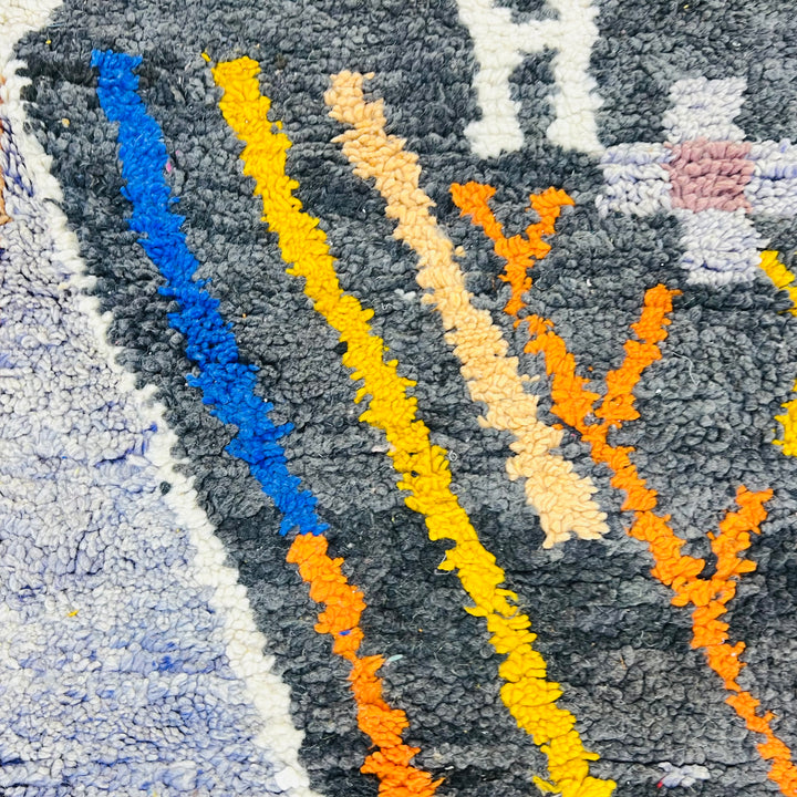 Colorful abstract pattern on vintage Moroccan wool rug with geometric lines in yellow, orange, and blue. Berber craftsmanship.