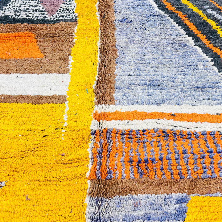 Colorful vintage Moroccan wool rug with geometric and abstract tribal patterns in yellow, orange, blue, and ivory tones.