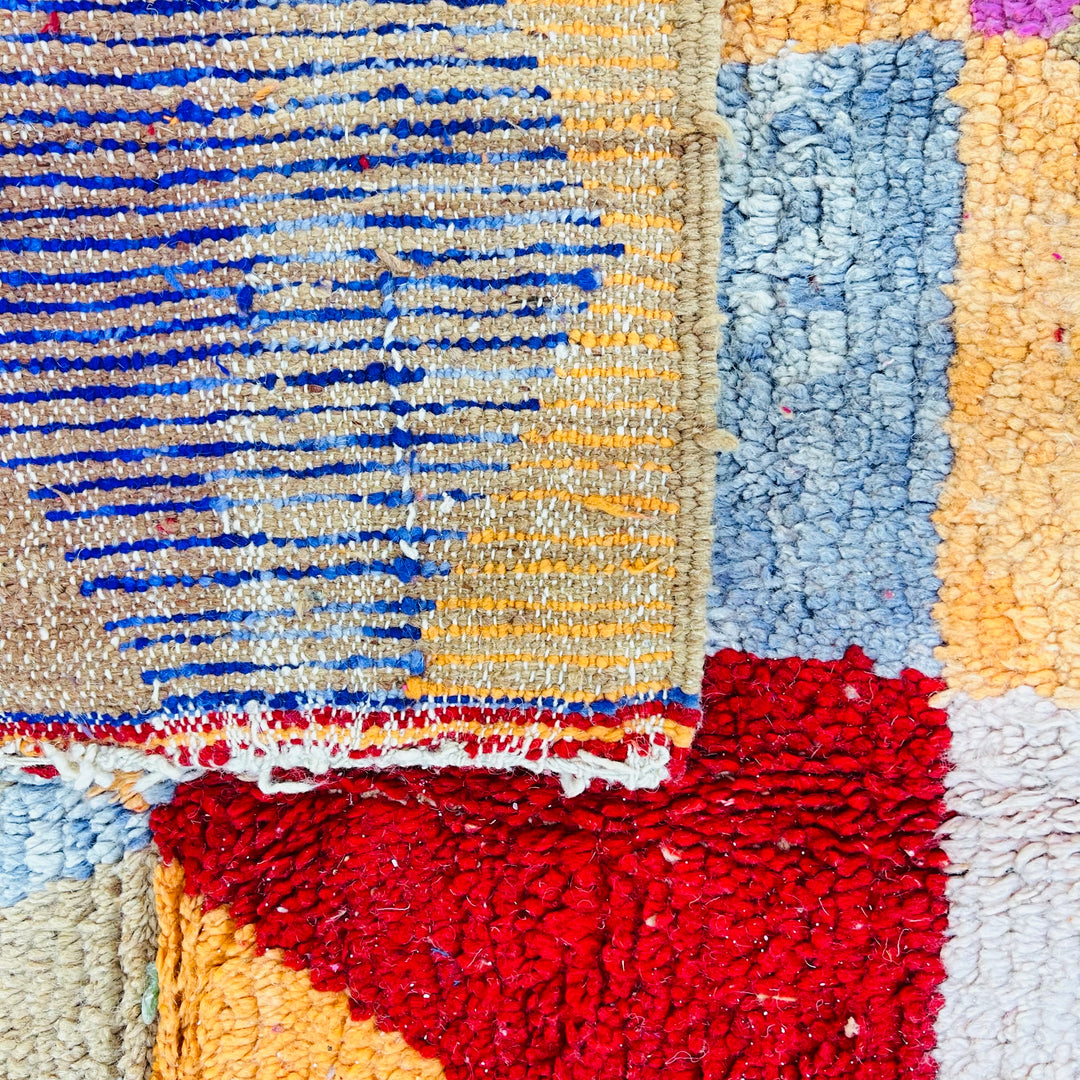 Colorful diamond vintage Moroccan rug with harlequin pattern in red, coral, ochre, pink, beige, and blue. Traditional Berber design.