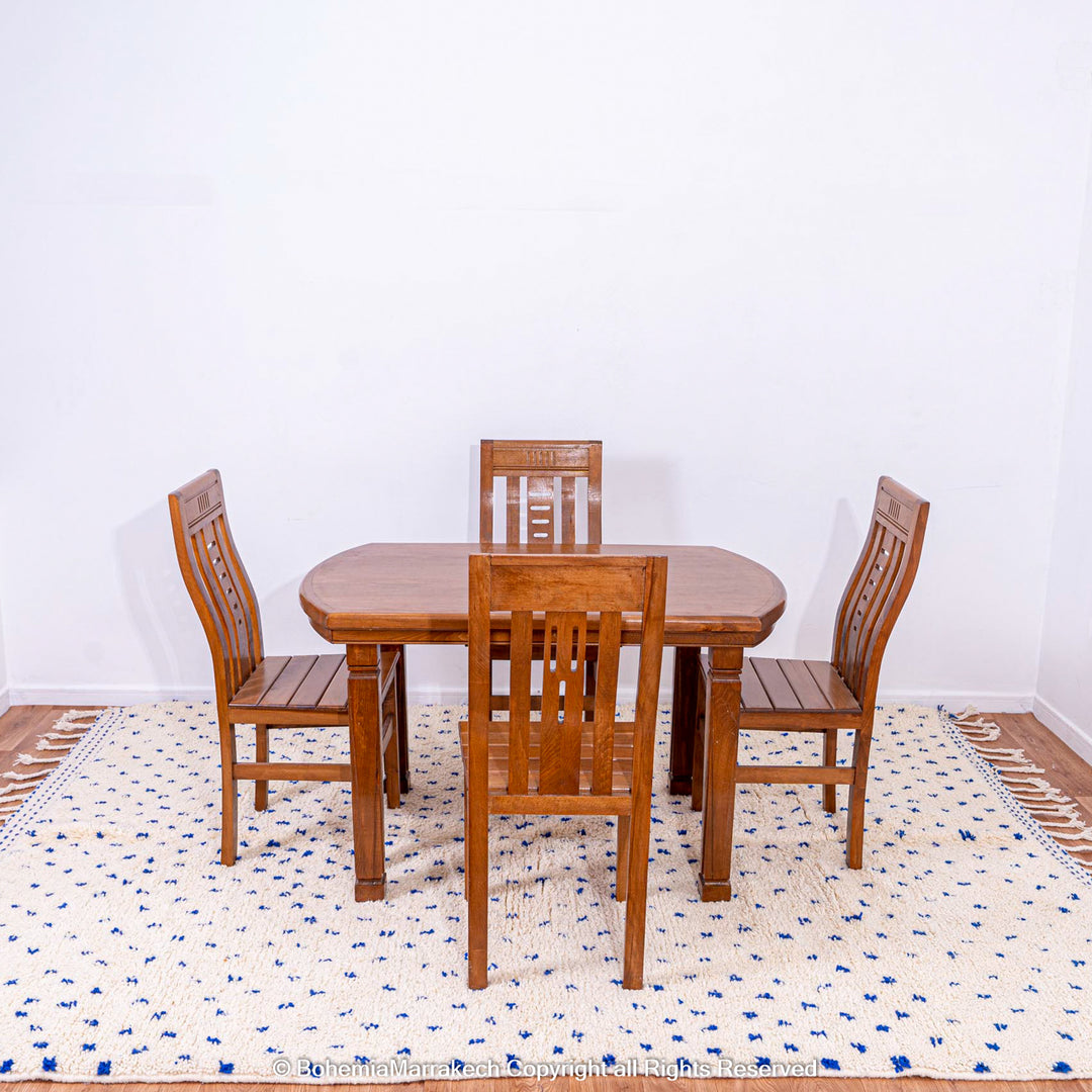 Large white Moroccan rug with blue dots under wooden dining table and chairs, showcasing Beni Ourain craftsmanship.
