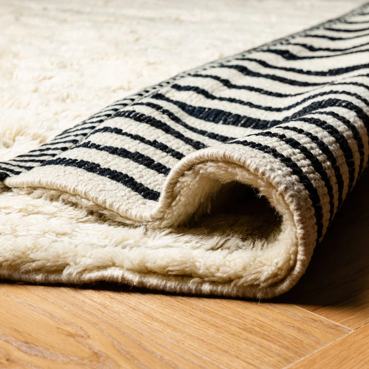 Close-up of a handmade Moroccan Beni Mrirt rug, featuring black and white stripes, woven with premium wool and traditional Berber techniques.